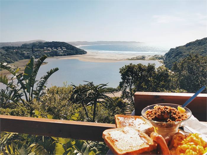 A breakfast plate on the deck with the beach and sea behind