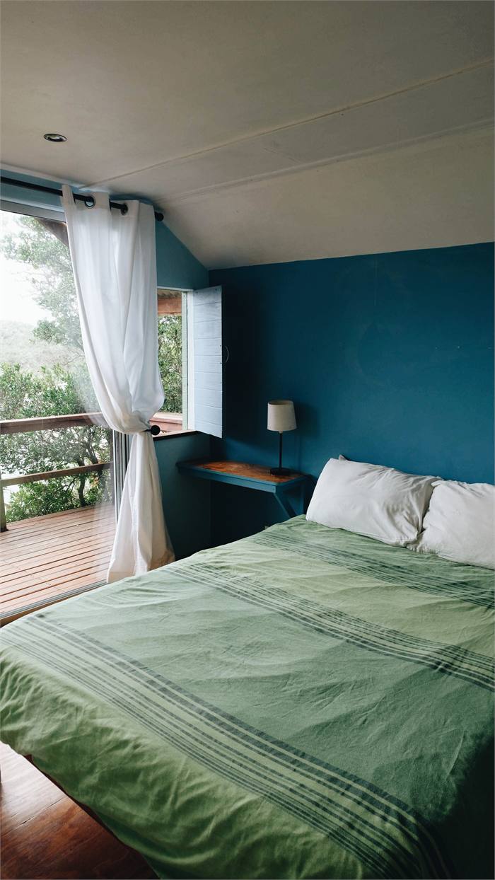 The budget double cabin with a green bedspread and doors to the deck
