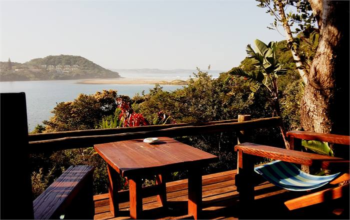A cottage deck with a table and deckchairs facing the bay