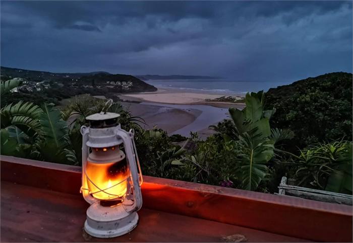 A storm lantern burning on a wall at dusk with the lagoon behind