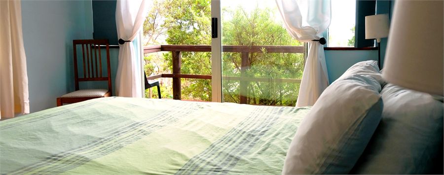 Budget en-suite room with a bed looking out through wide windows towards the lagoon