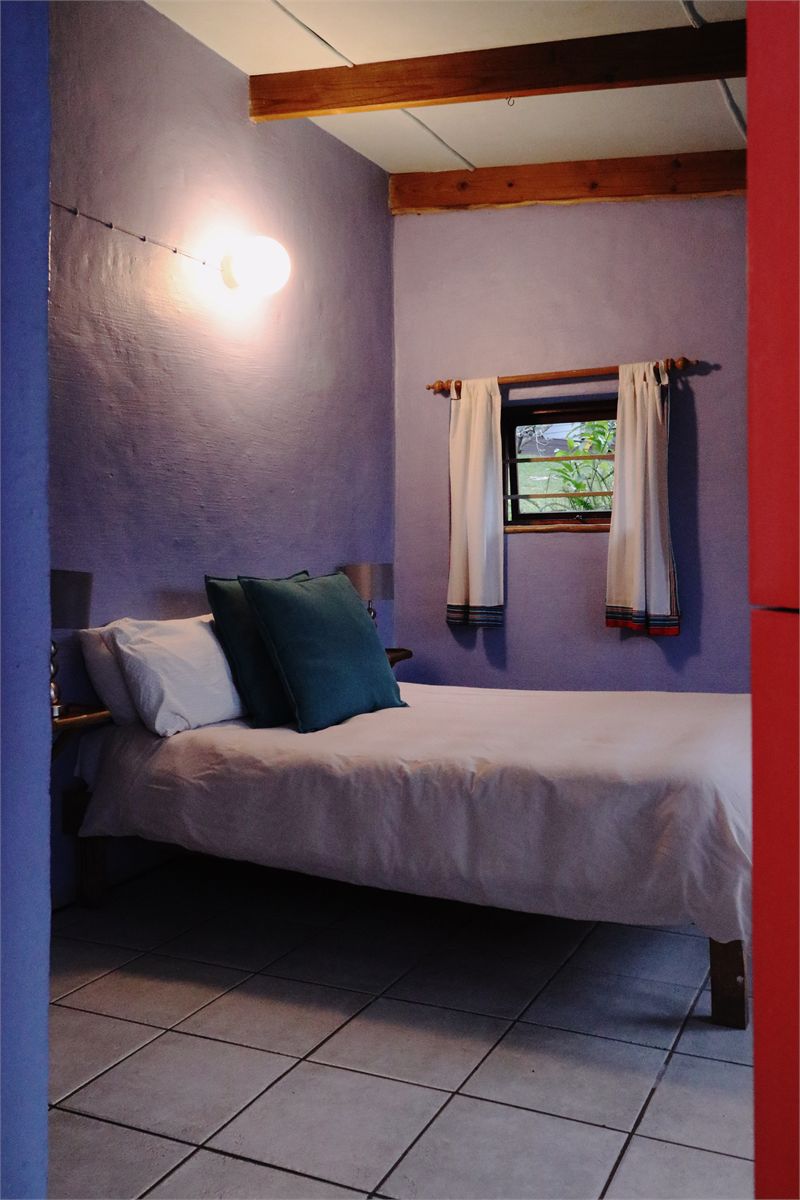 Garden cottage bedroom with a red door and morning light through the window