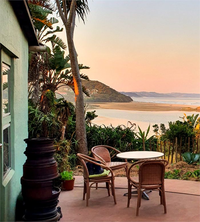 Cottage patio with wicker chairs overlooking the lagoon at sunset
